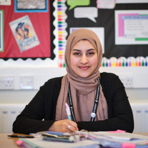 TA P165 Brown female student wearing a headscarf studying in a sixth form classroom.